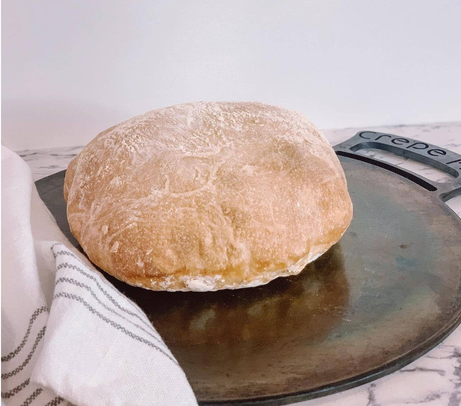 Spreading fresh crepe batter on a seasoned carbon steel pan